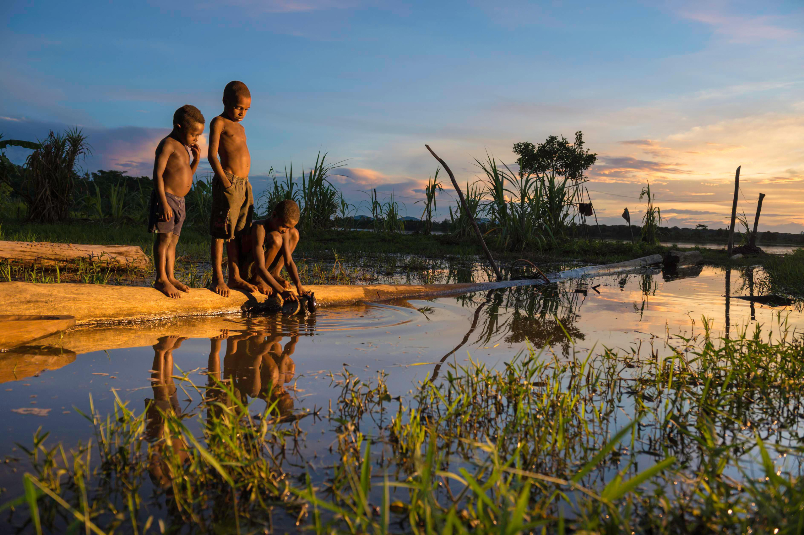 Children bathe in the Sepik River at sunset